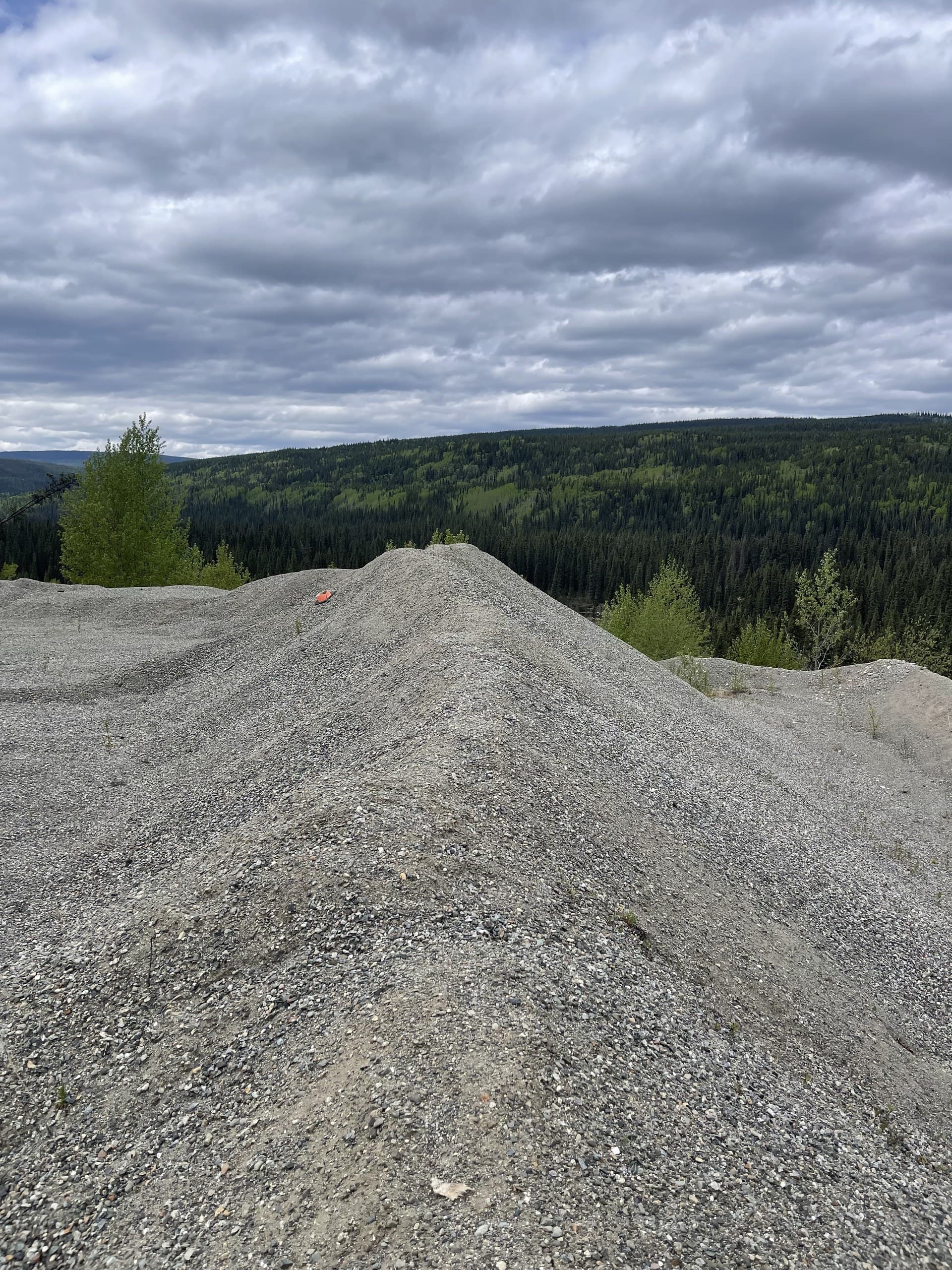Crushed aggregate stockpile on a pit floor under an overcast sky