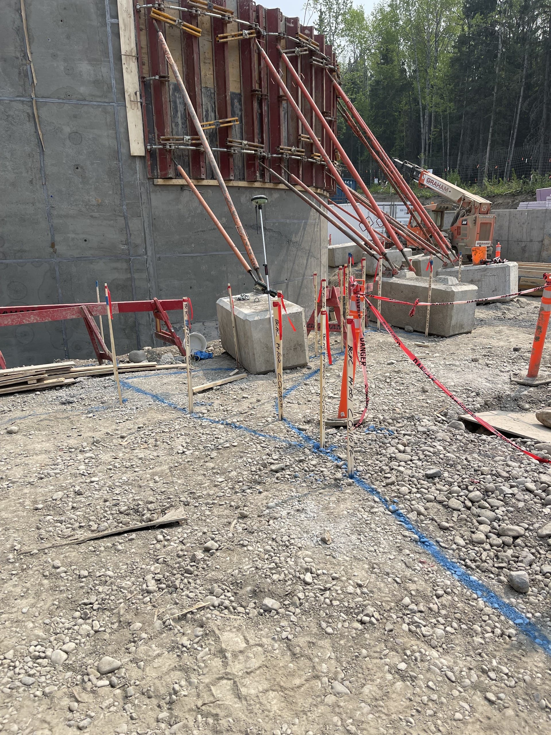Layout lath and survey rover among concrete footings on an active construction site