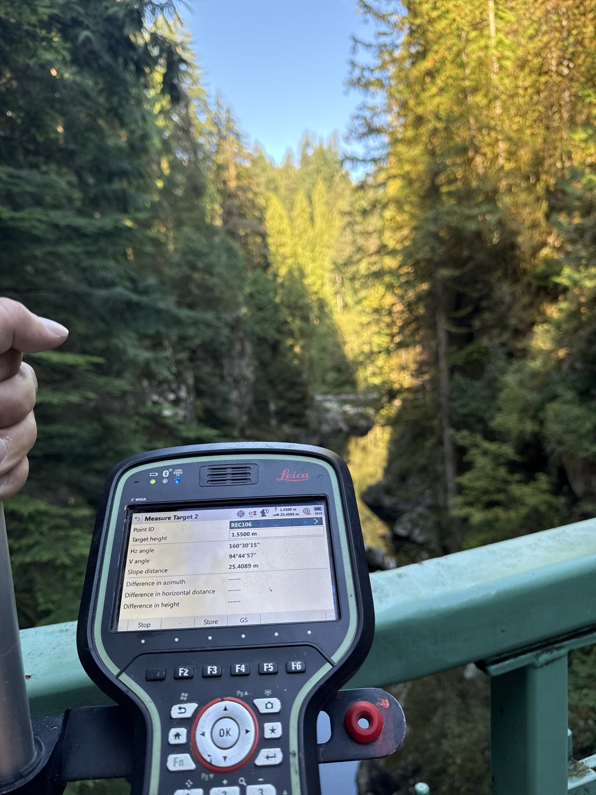 Field controller measuring from a suspension footbridge over a creek