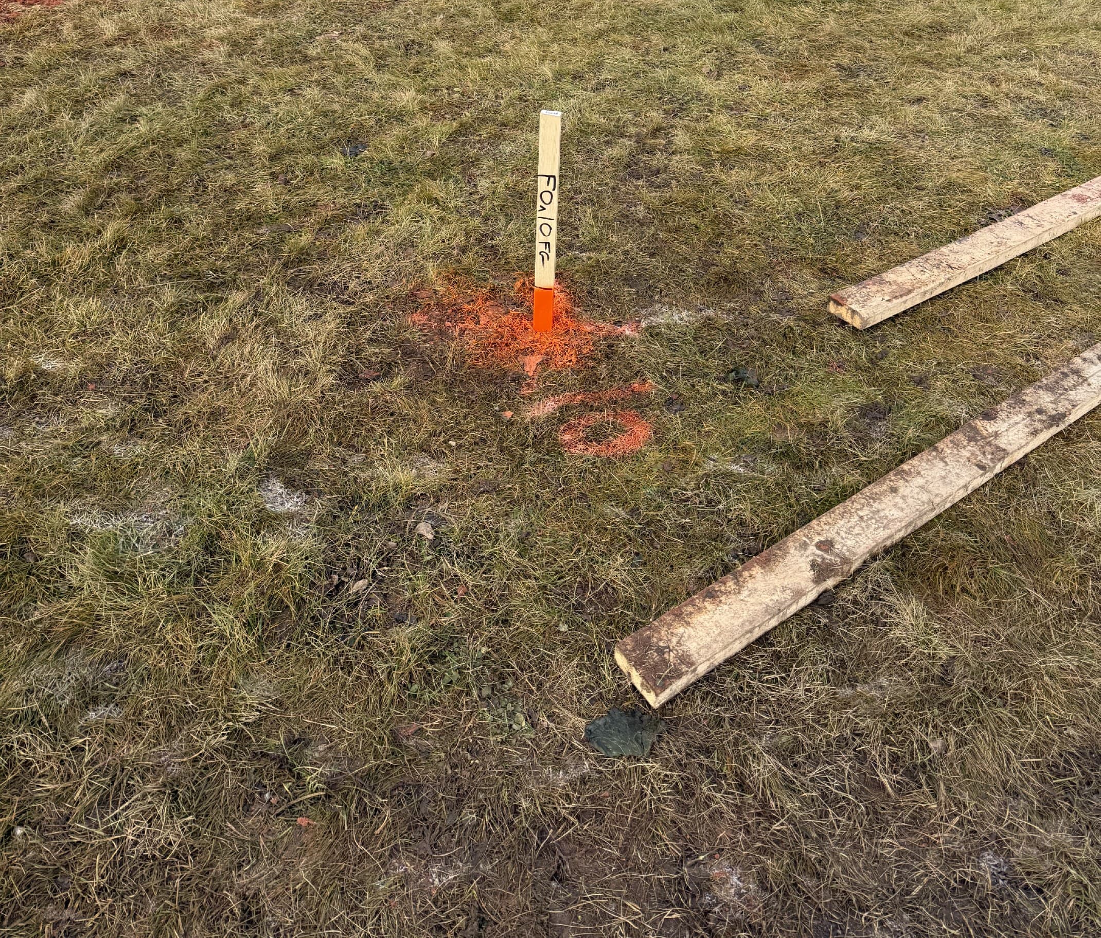 Foundation offset stake with orange paint on a cleared site