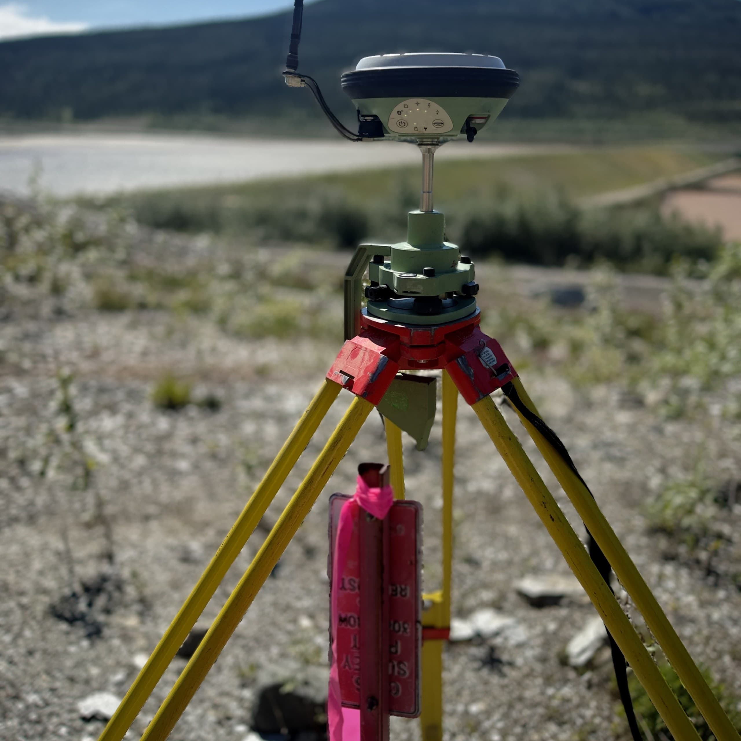 GNSS receiver set up over a marked control point with mountains behind