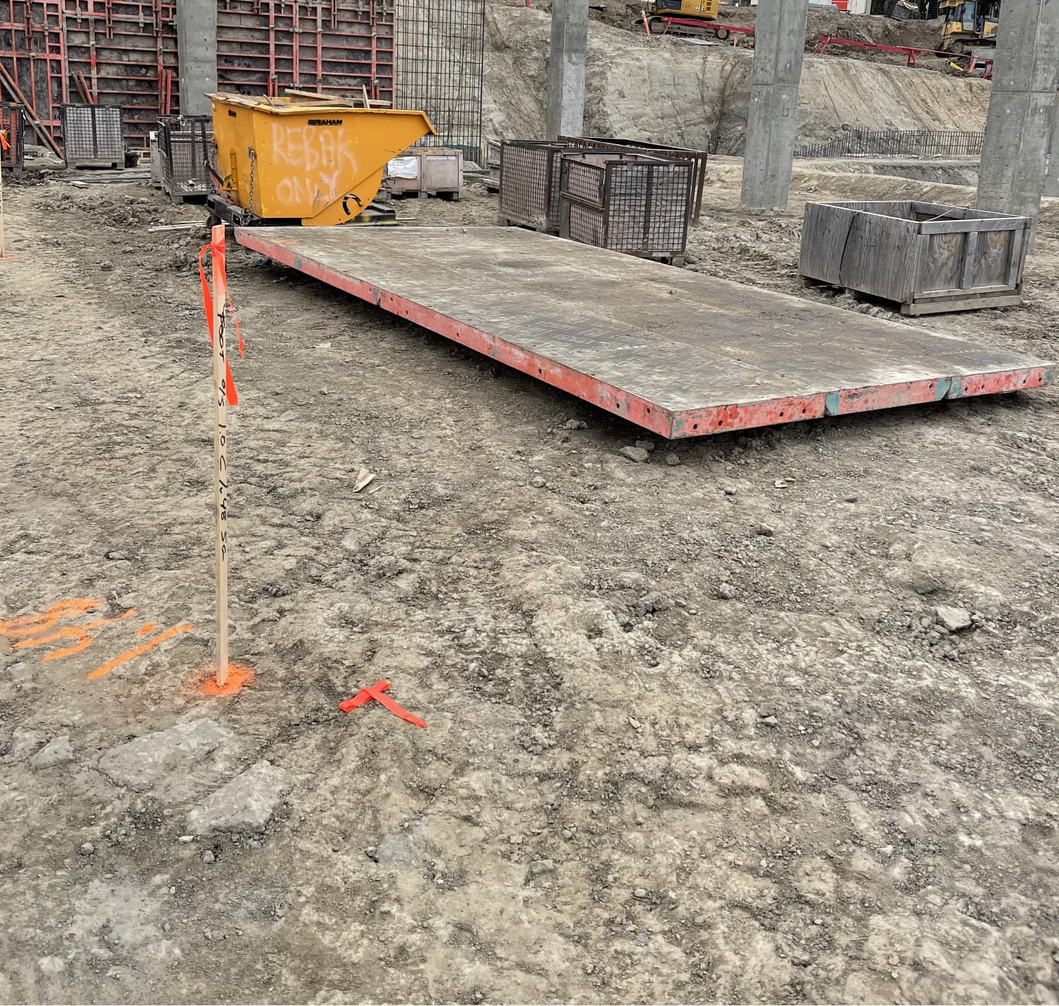 Layout stake and paint marks on a stripped building pad