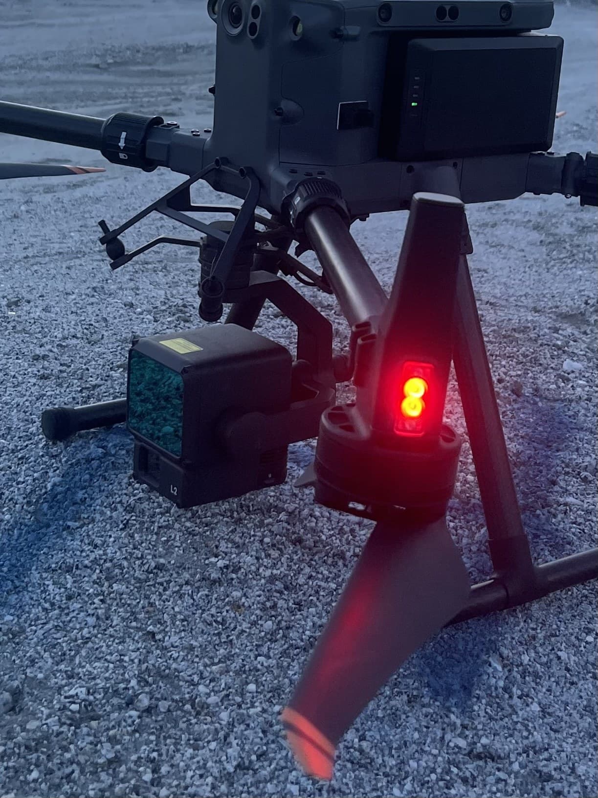 Heavy-lift survey drone with LiDAR payload staged on gravel at dusk