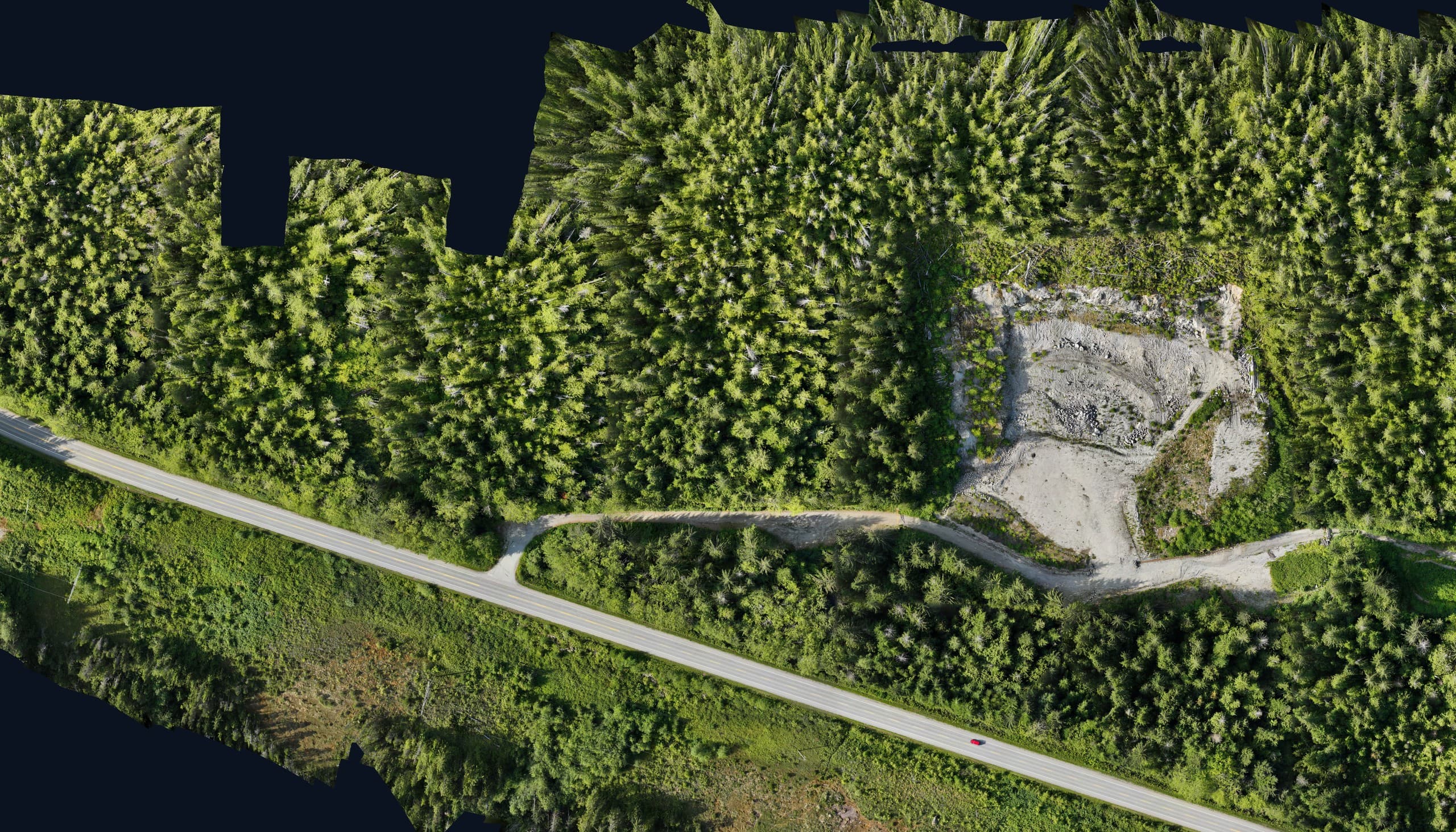 Drone orthophoto of a gravel pit and highway corridor through forest