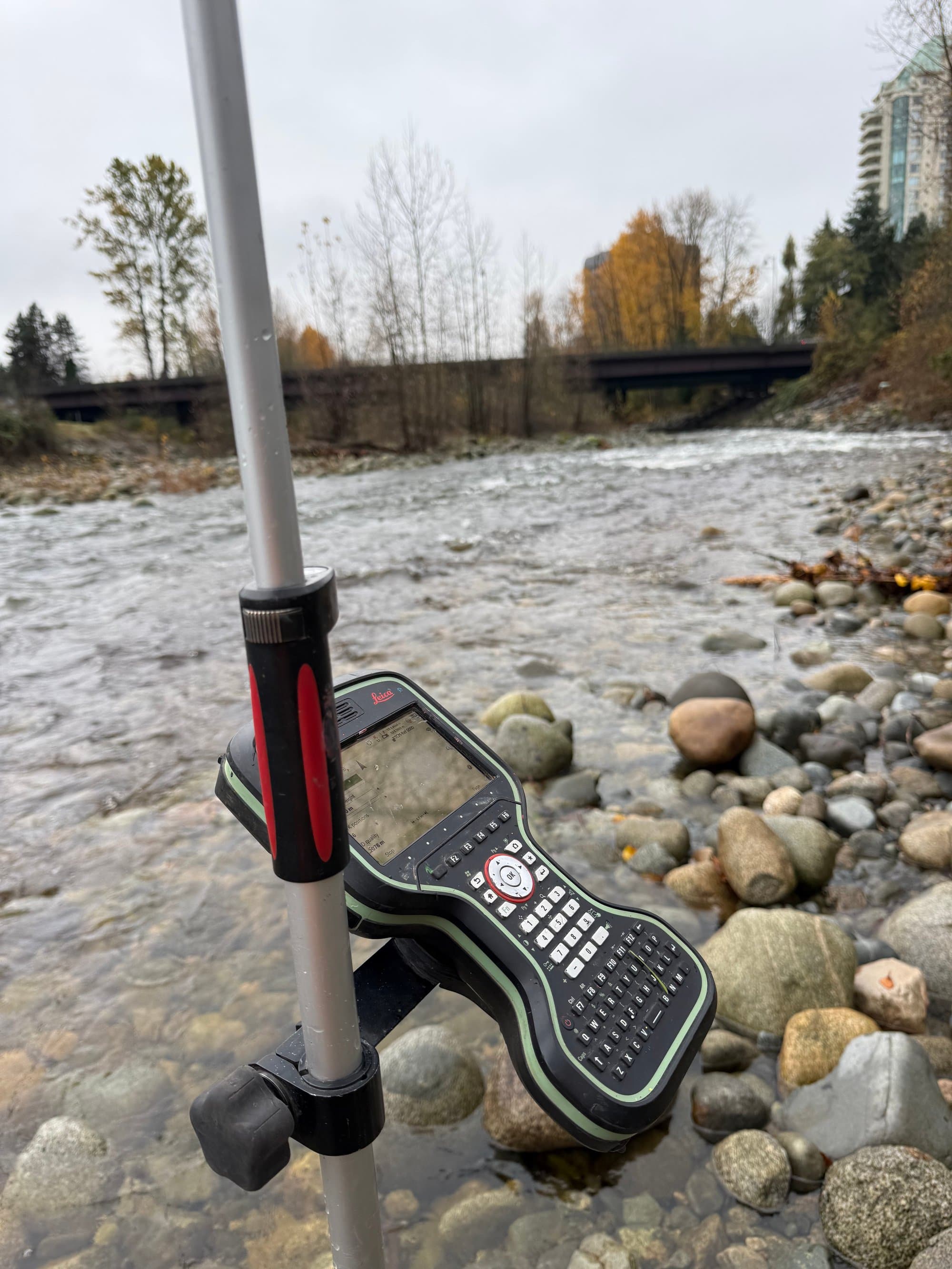 Field controller on a survey rod beside a river channel